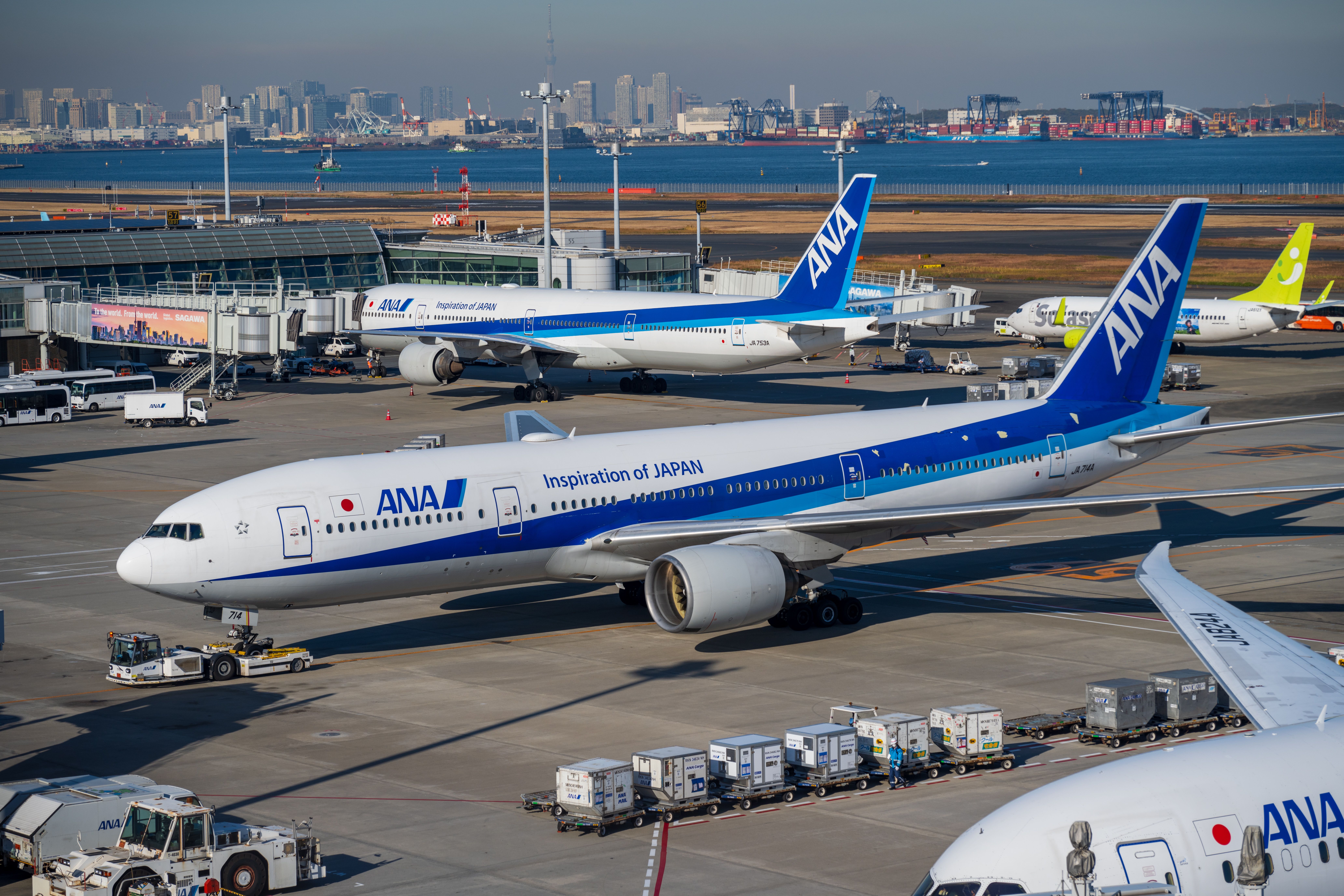 ANA Boeing 777 aircraft on the tarmac at Haneda Airport Tokyo with Tokyo Bay and city skyline in the background