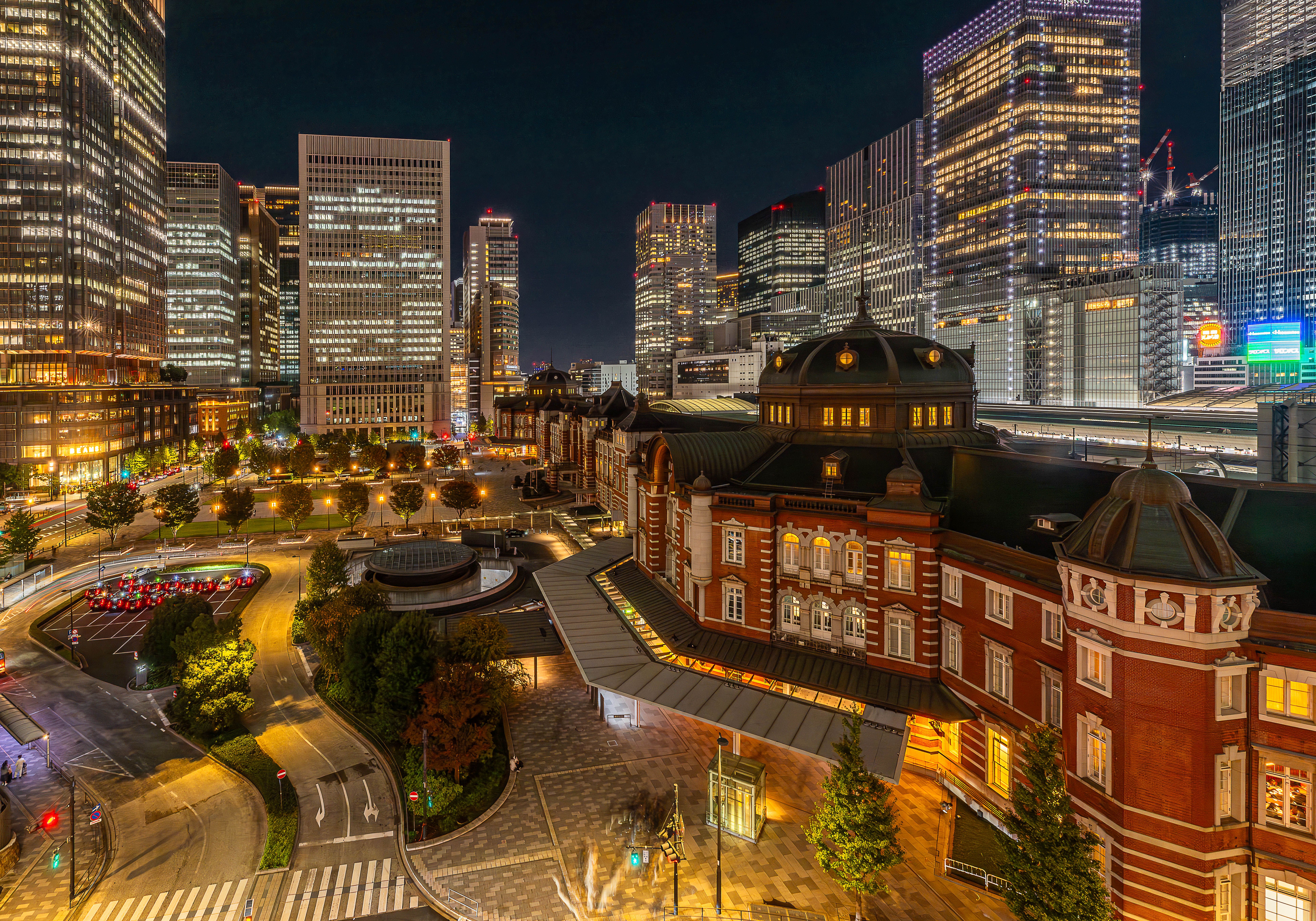 Tokyo Station historic red brick building illuminated at night with Marunouchi skyscrapers glowing behind it